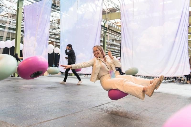 Dame i lyse klær sitter på slengdisse som er satt opp innendørs i konferansehall.