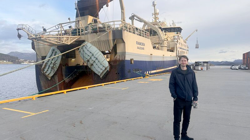 Mann står foran et skip.