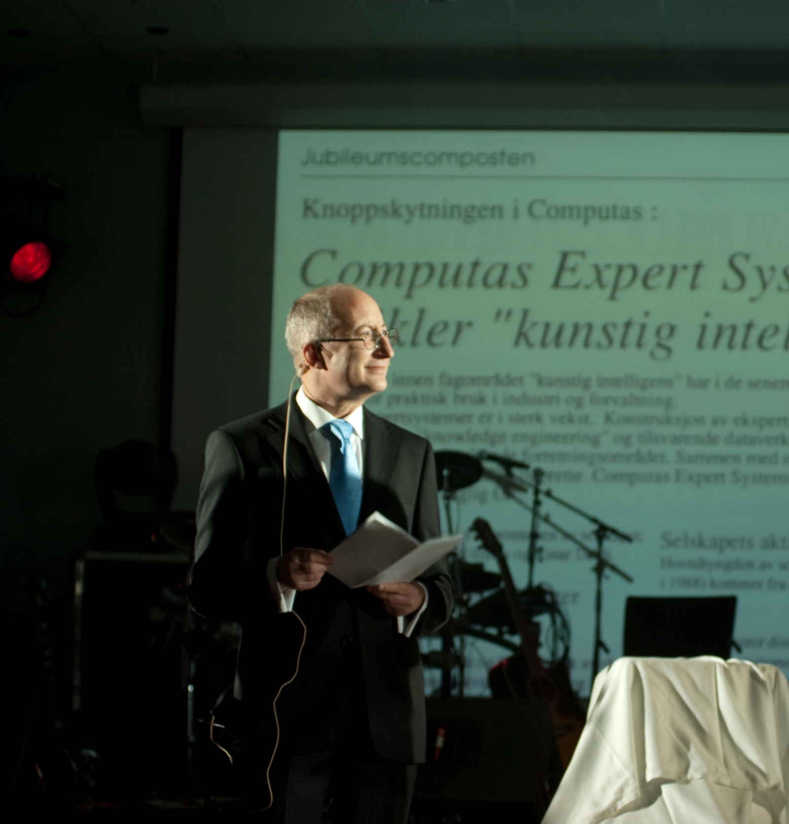 Dresskledd mann står på en scene.