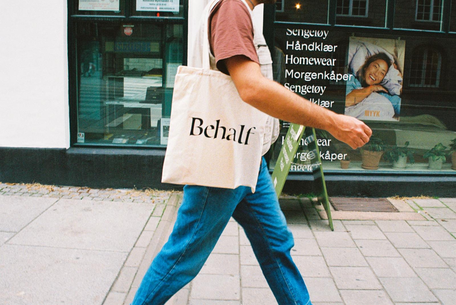Mann går på fortauet med et Behalf-handlenett.