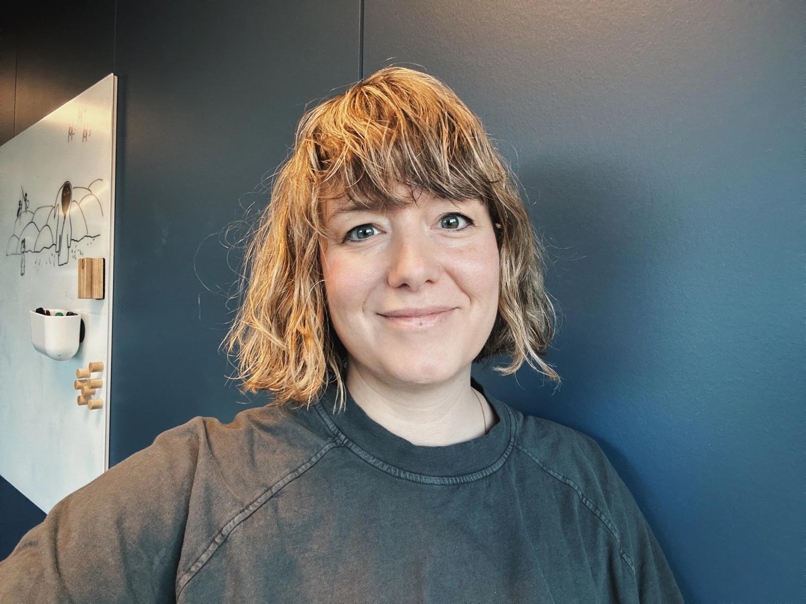 Dame med grønne øyne og kort, lyst hår som når ned til skuldrene.