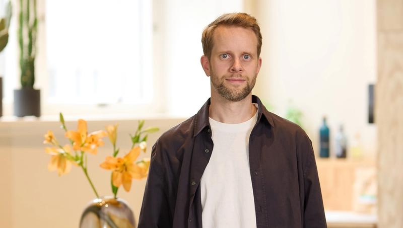 Portrettbilde av mann med kort skjegg og blå øyne i kontorlanskap.