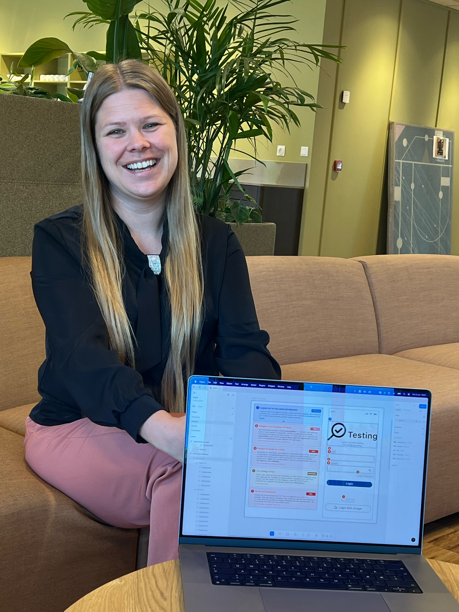 Portrett av en smilende dame med langt lyst hår som sitter i en sofa. Foran henne står det et lavt bord med en laptop og en kopp te.