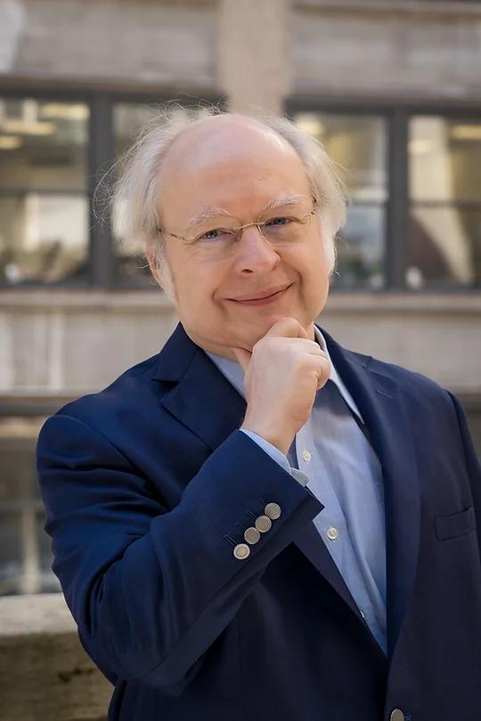 Mann i dress holder hånden opp mot haken med et tenkende utrykk.