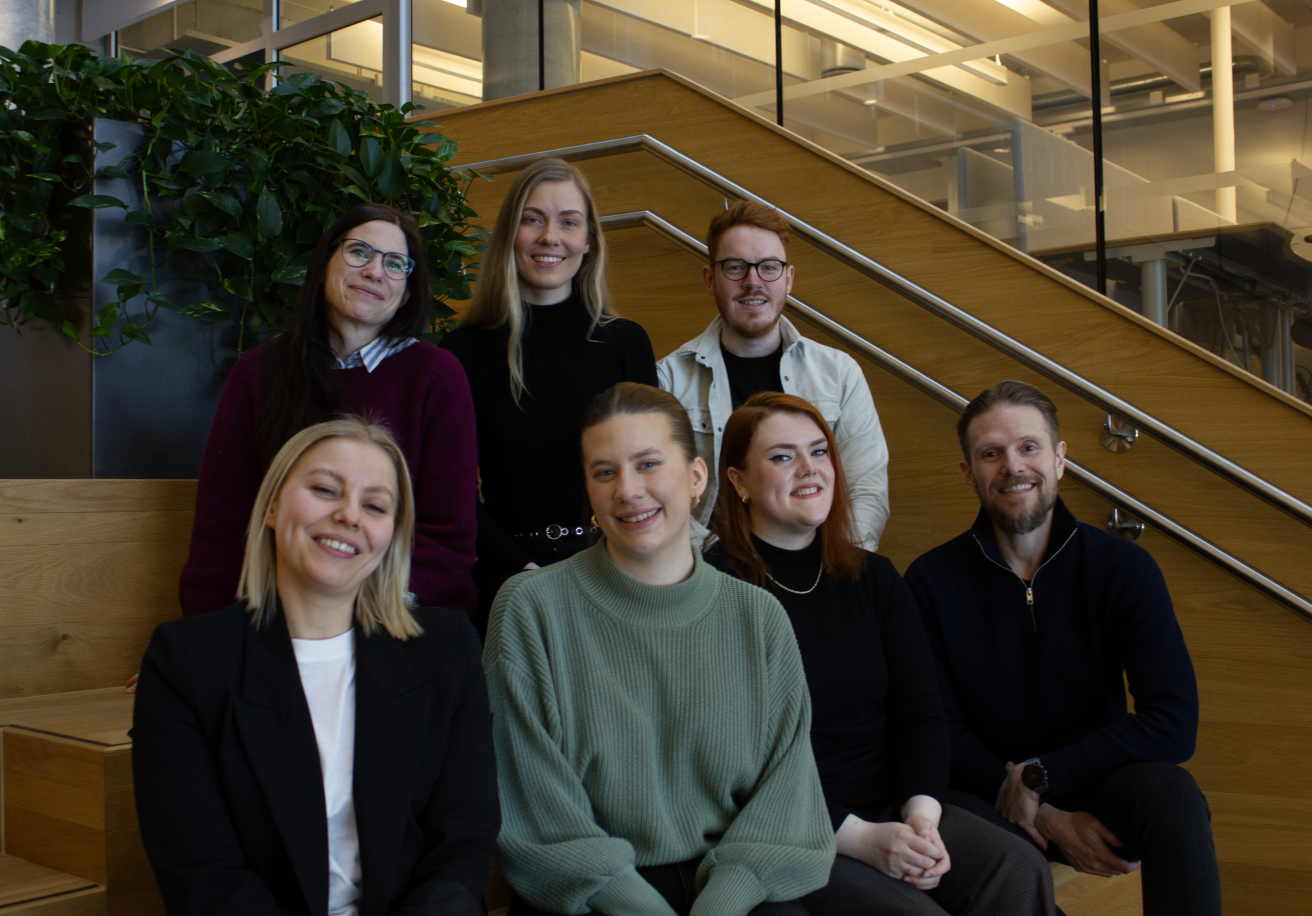 7 Tieto Evry ansatte, fra Trondheimskontoret, sitter samlet for å ta bilde. På bildet fra venstre til høyre: Øverst bak har vi Camilla Stenkløv Illøkken, Mia Tangvik, Frikk Alexander Odlolien Foran er Anne Folgerø, Marit Spjøtvold, Linn Sortebech, Roar Gjøvaag. Bildet er tatt på Tietoevrys kontor i Trondheim.