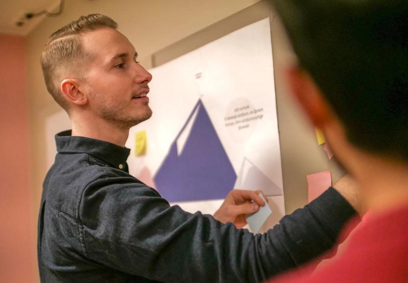 Andreas Hartveit henger Post-its på en tavle.