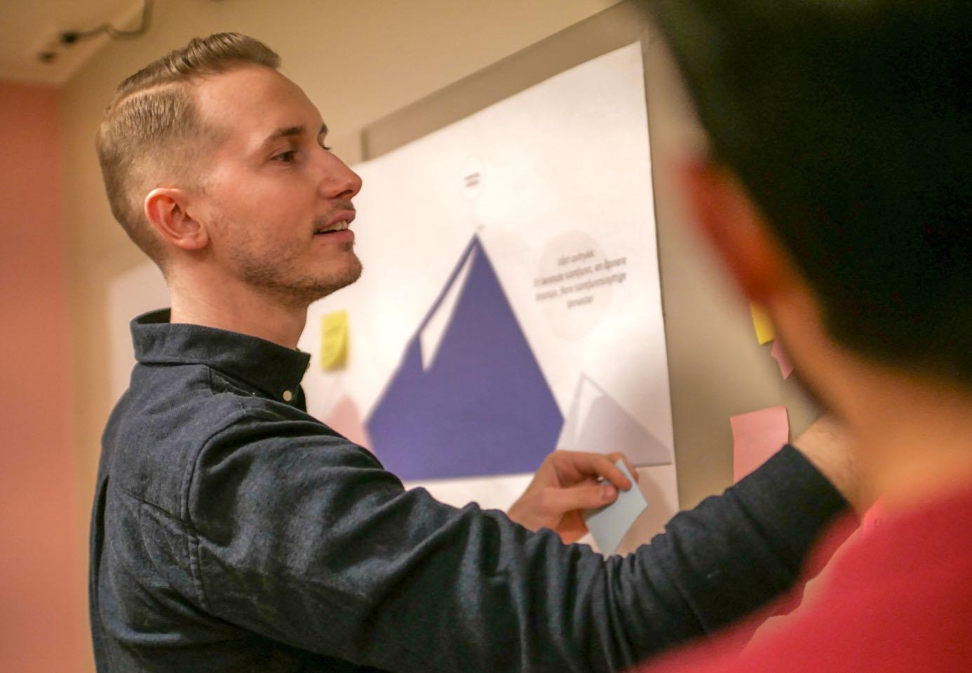 Andreas Hartveit henger Post-its på en tavle.