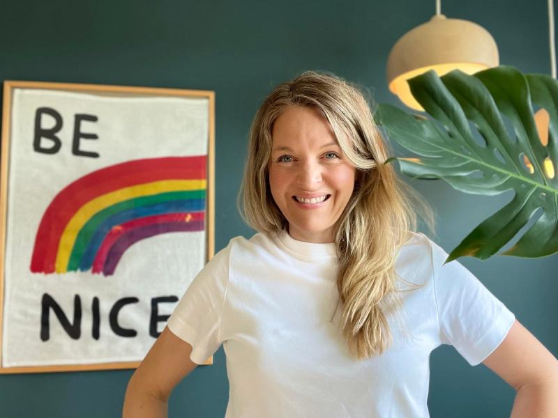 Anne Aagaard smiler med teksten "Be nice" rammet inn i bakgrunnen.