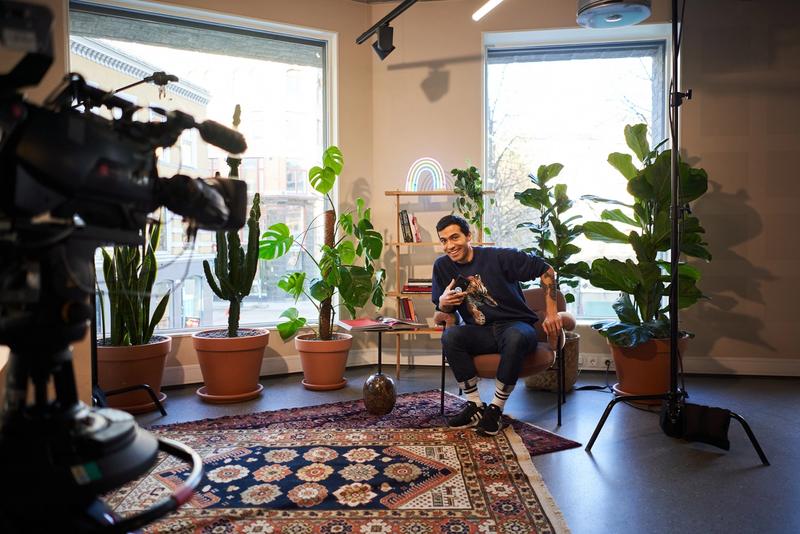 Daniel sitter i en stol i et rom hos Netlife med masse grønne planter.