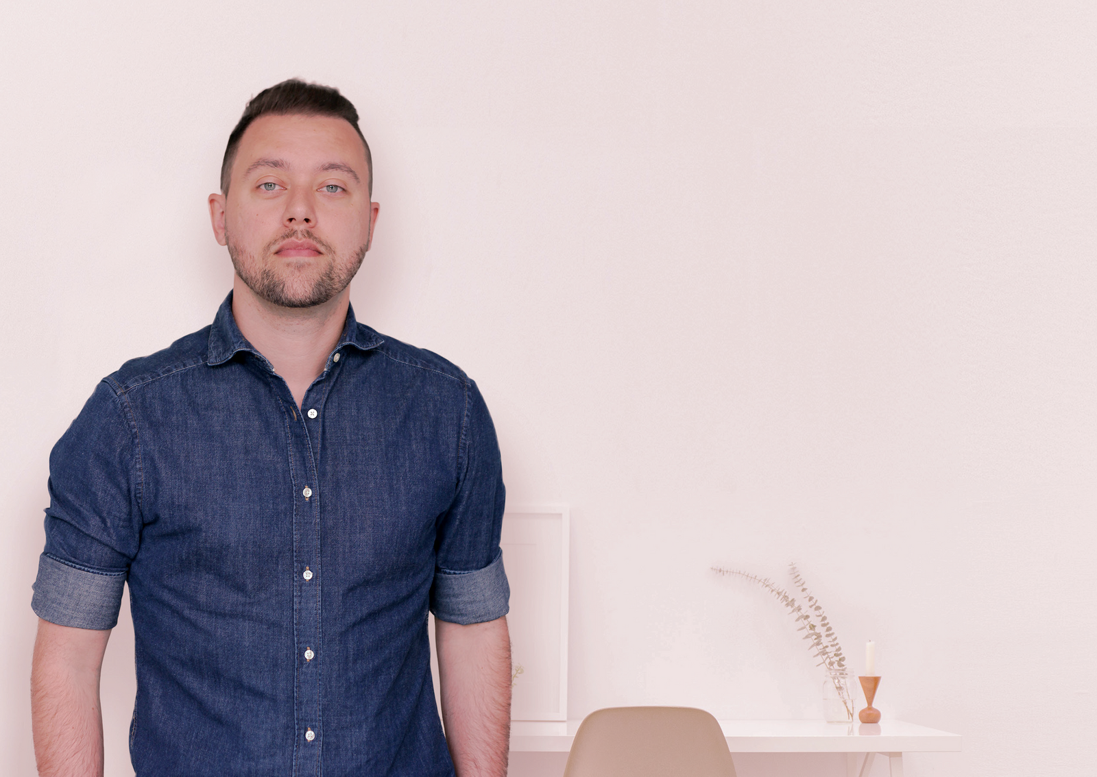 Mann med dongeri-skjorte står i hvit kontor og ser inn i kamera.