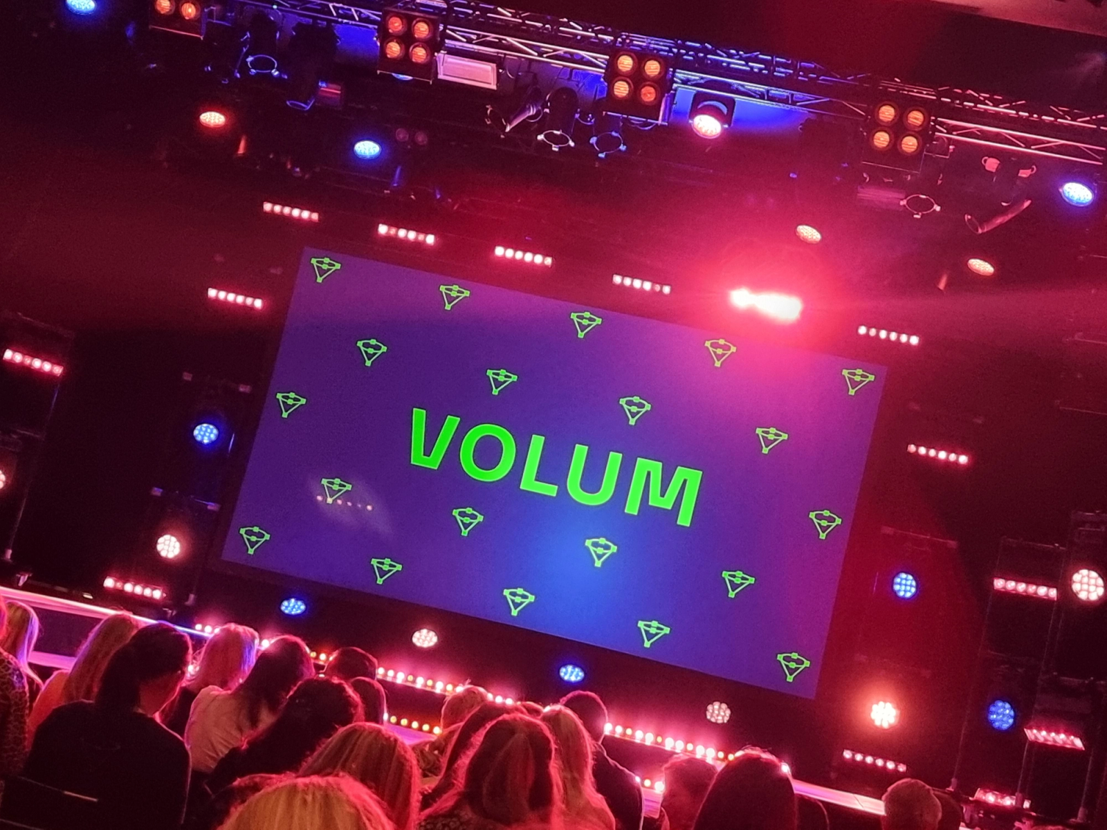 Opplyst scene med logoen til Volumkonferansen foran et publikum. Foto