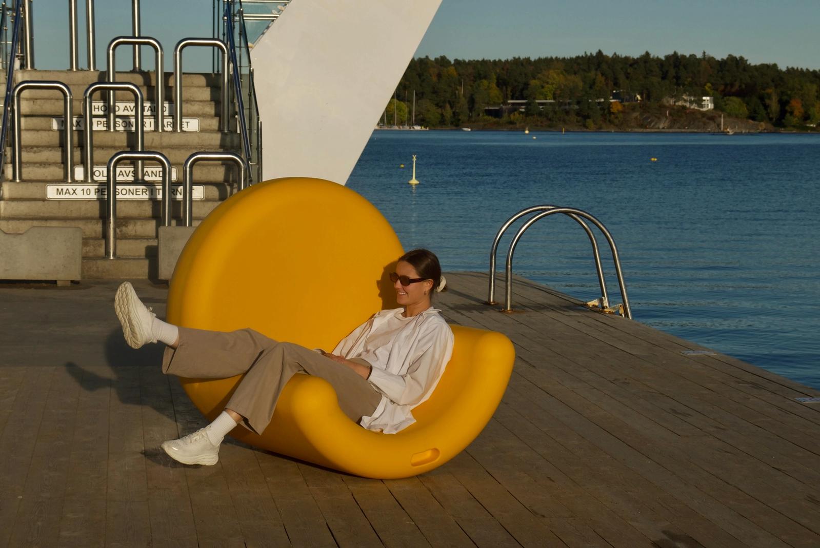 Iris sitter i en stor gul stol på en brygge.