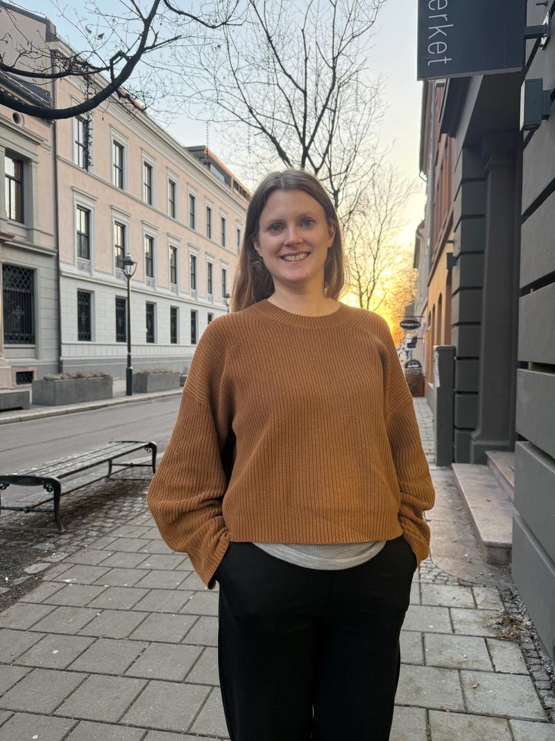 Blond dame i ullgenser står utendørs.