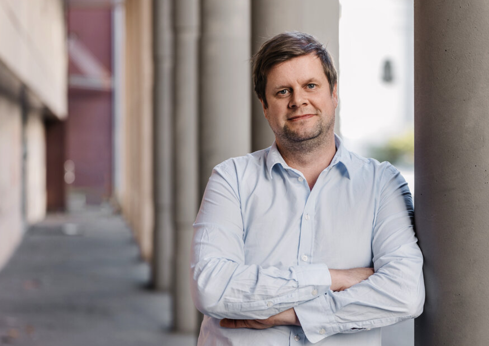 Mann i lys blå skjorte med armene i kryss