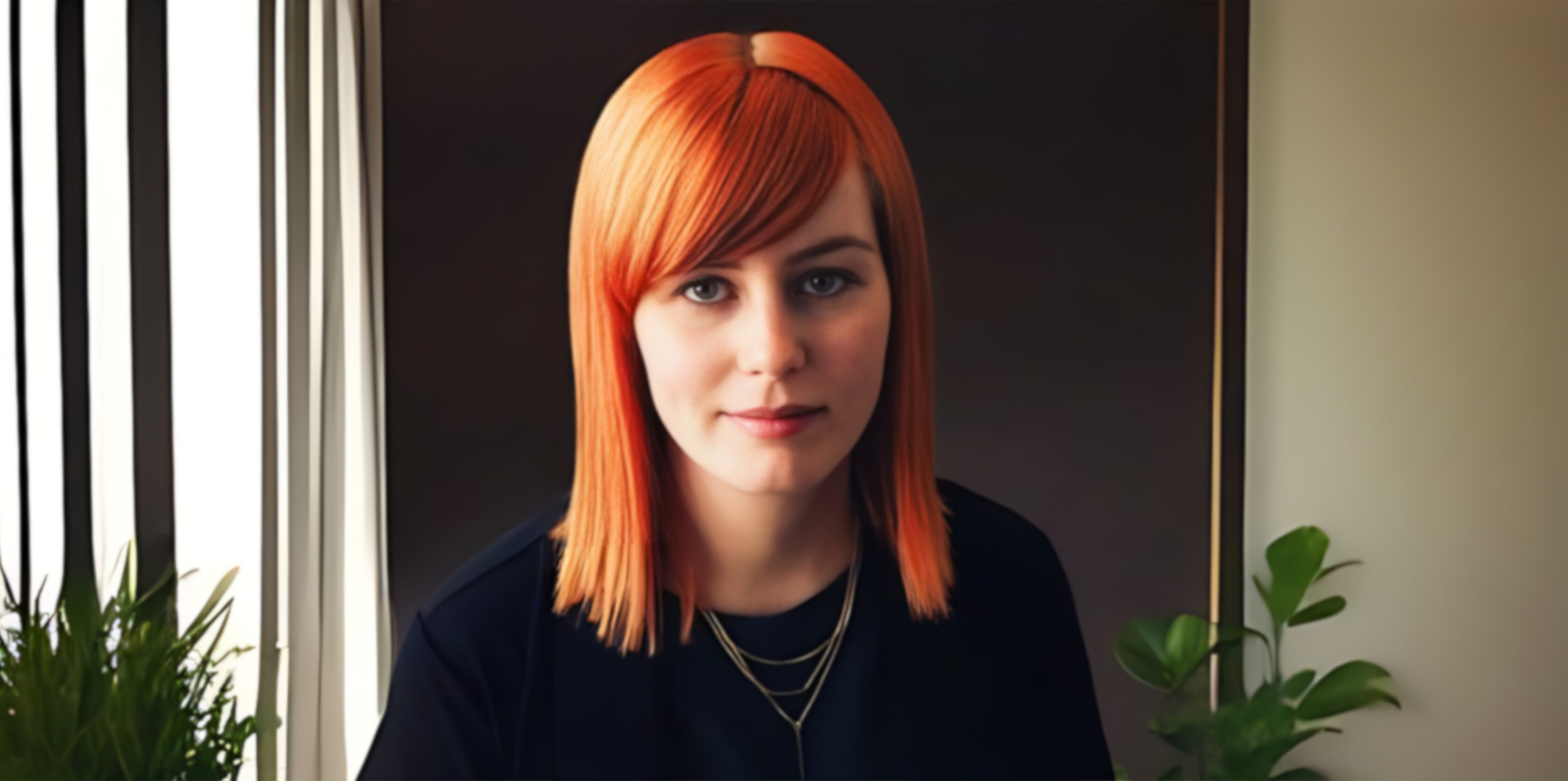 Portrett av Sandra Oen. Hun har stritt hår med lugg ned til skuldrene. Håret er i en sterk orange farge, som står i kontrast til hennes svarte klær. 