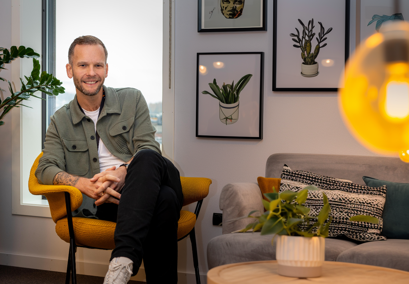 Mann sitter i en stol med plakater av illustrerte kaktuser bak seg.