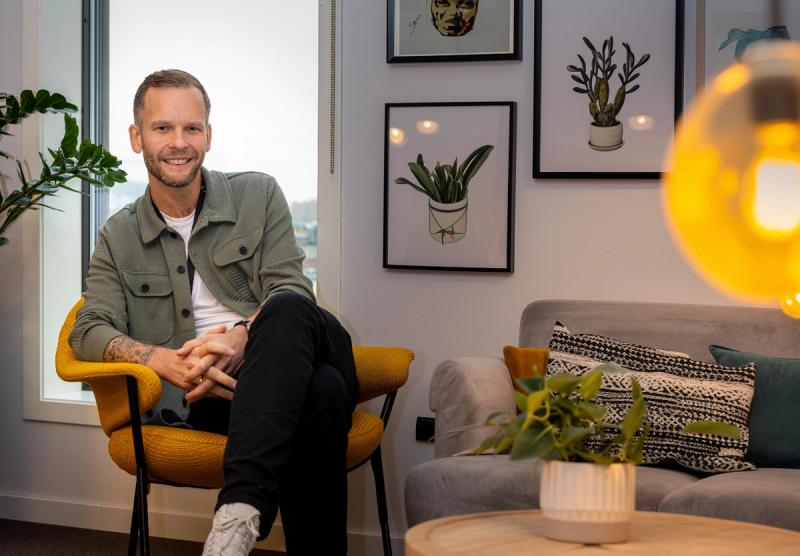 Mann sitter i en stol med plakater av illustrerte kaktuser bak seg.