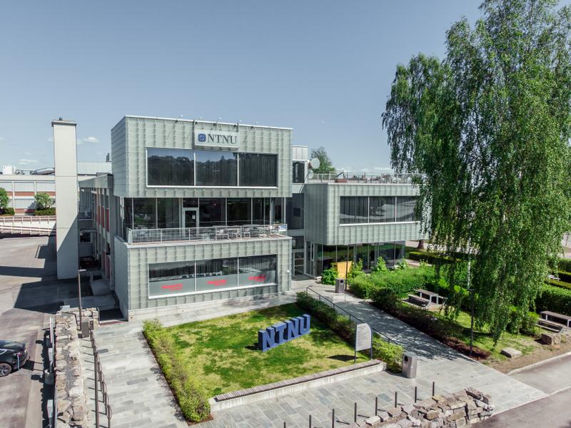 Bilde av bygg med plen foran med NTNU-bokstaver på