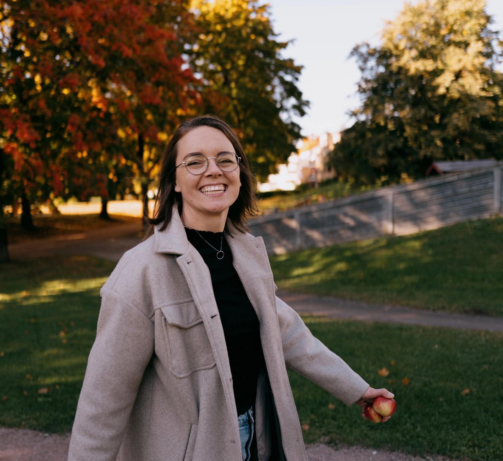 Kvinne går ute i en park og smiler