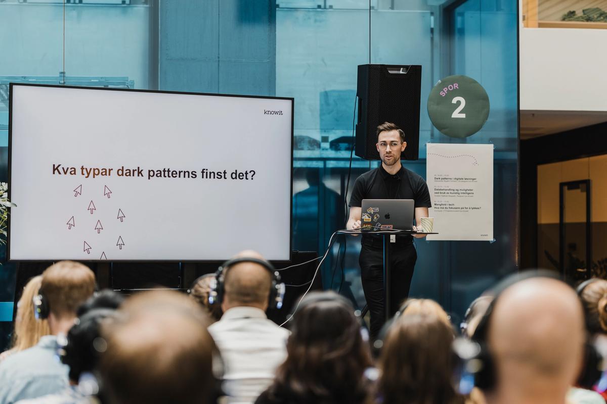 Person holder foredrag om dark patterns foran en forsamling.