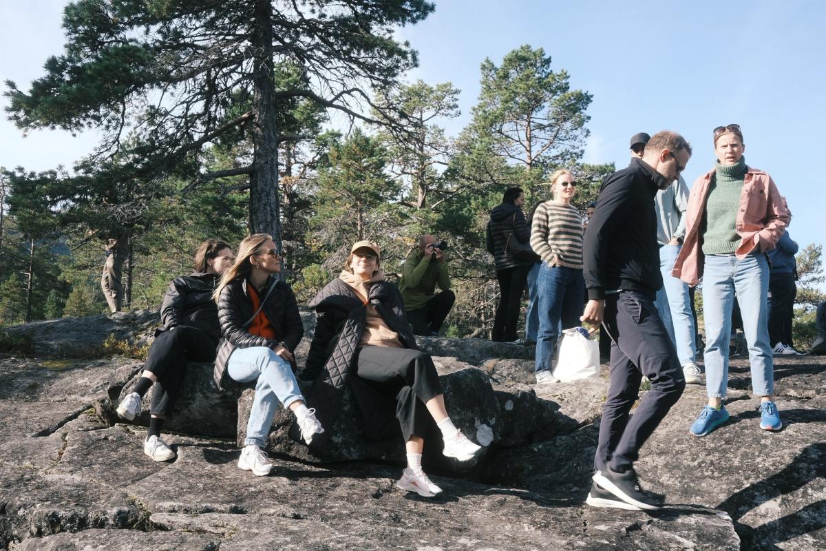 Mennesker sitter pÄ et berg med skog bak seg.