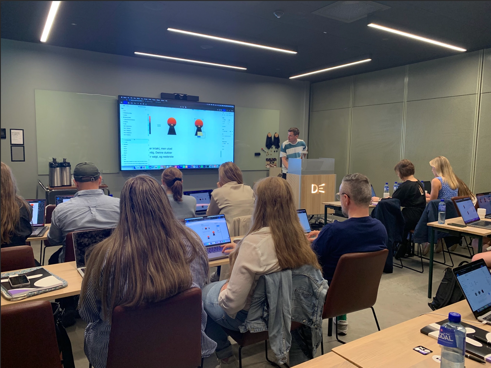 Mann som snakker foran folk med en skjerm