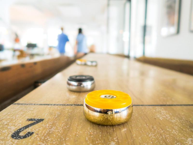 Brett med shuffleboard brikker gul og svart