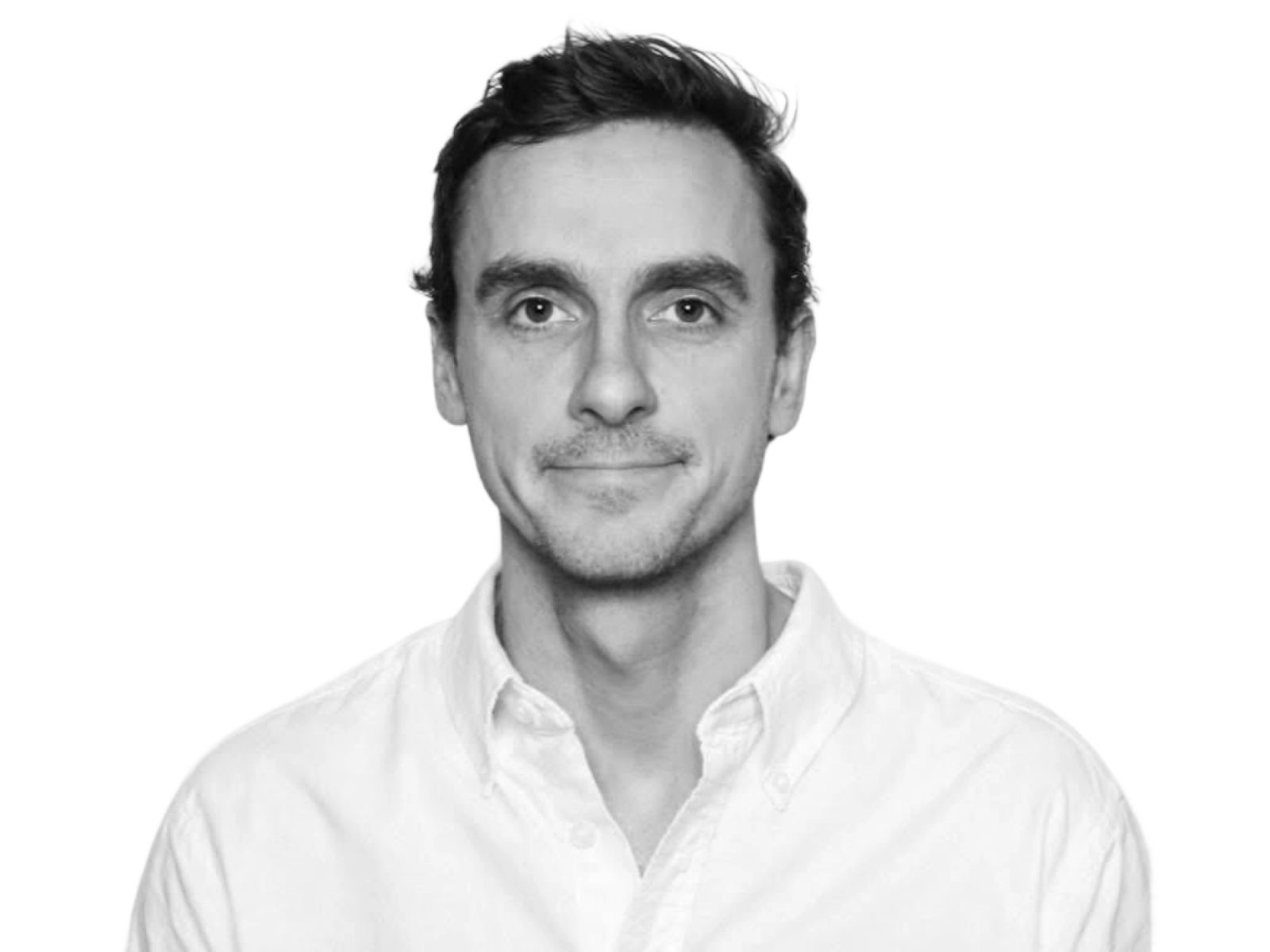 Svart hvitt bilde av mann med hvit skjorte og kort hår. Han har het nøytralt ansiktsutrykk.