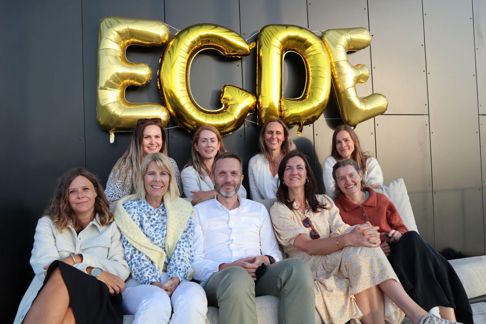 Konsulenter fra Egde sitter samlet på en sofa under gullbalonger som er formet som bokstavene E G D E