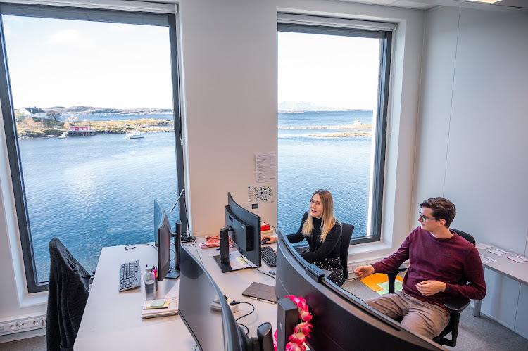 Mann og dame sitterpå et kontor foran datamaskiner.