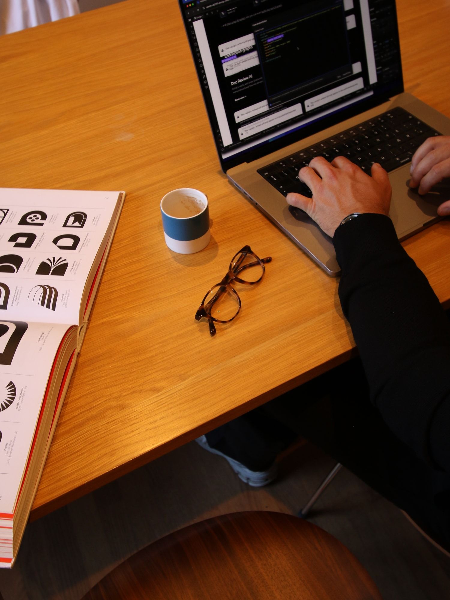 Laptop, espresso and a design book on a wooden desk