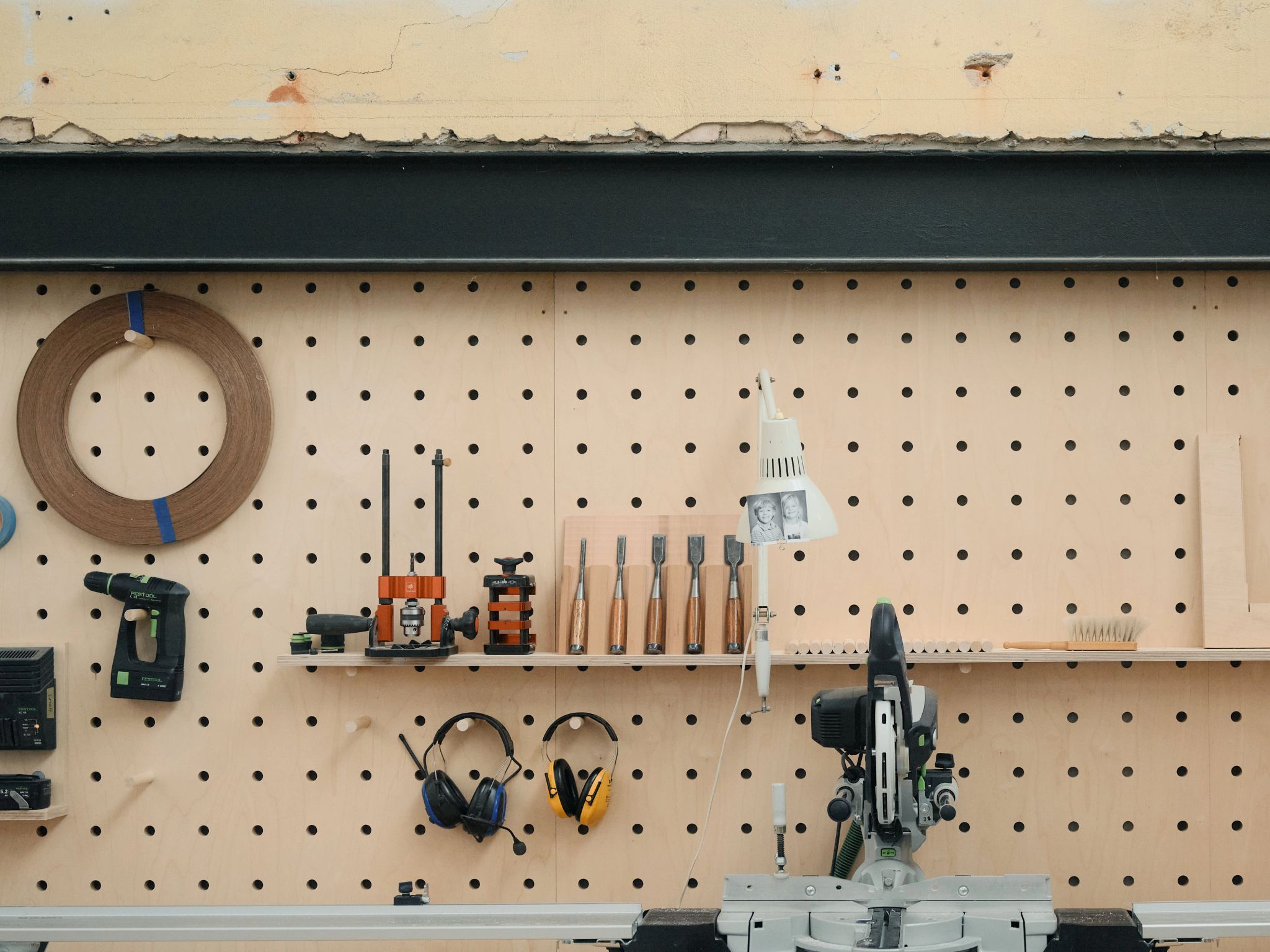 Woodworking tools and equipment neatly arranged on a pegboard wall in a workshop.