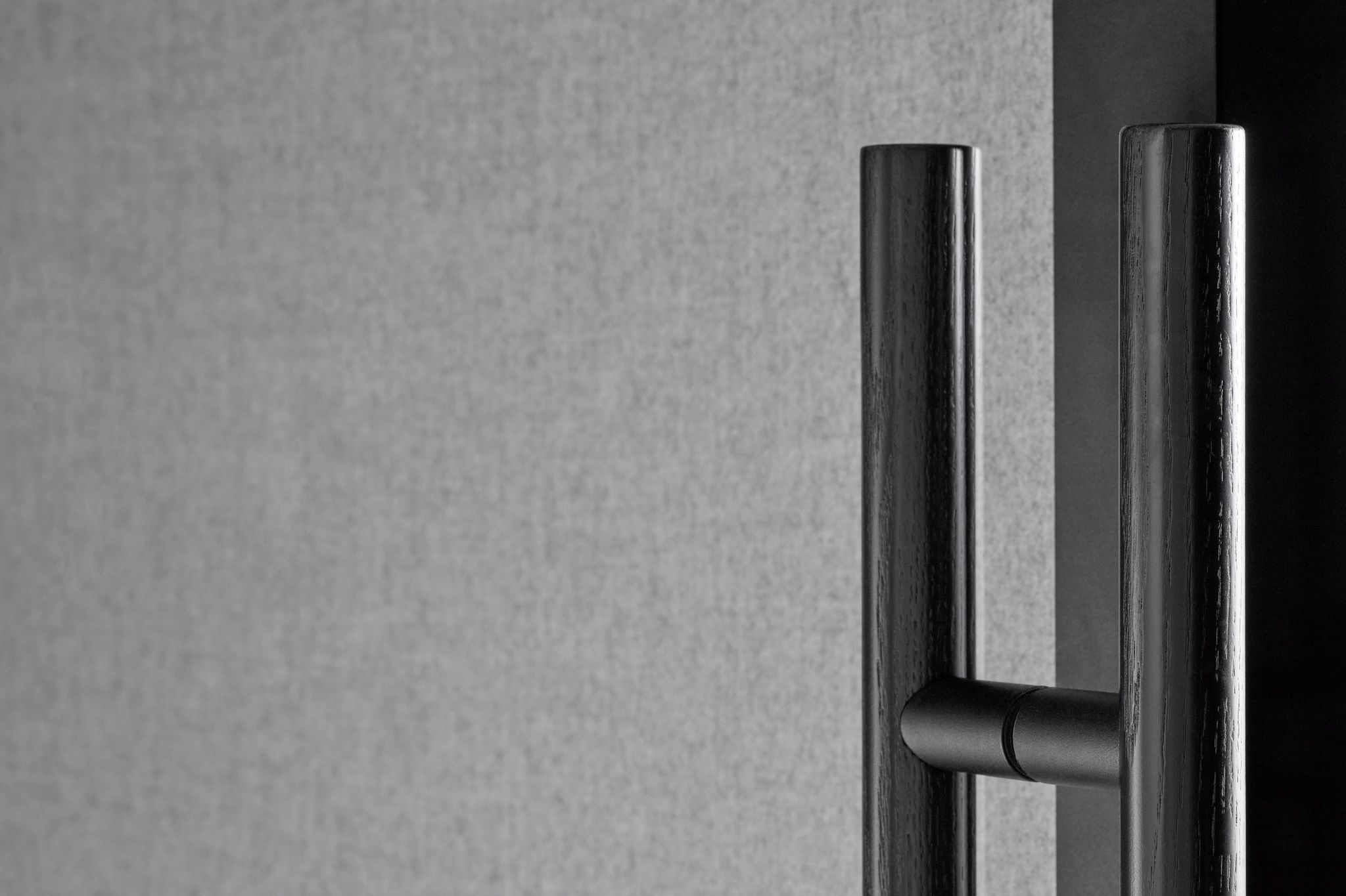 Close-up of dark Zen Pod door handle on textured wall background