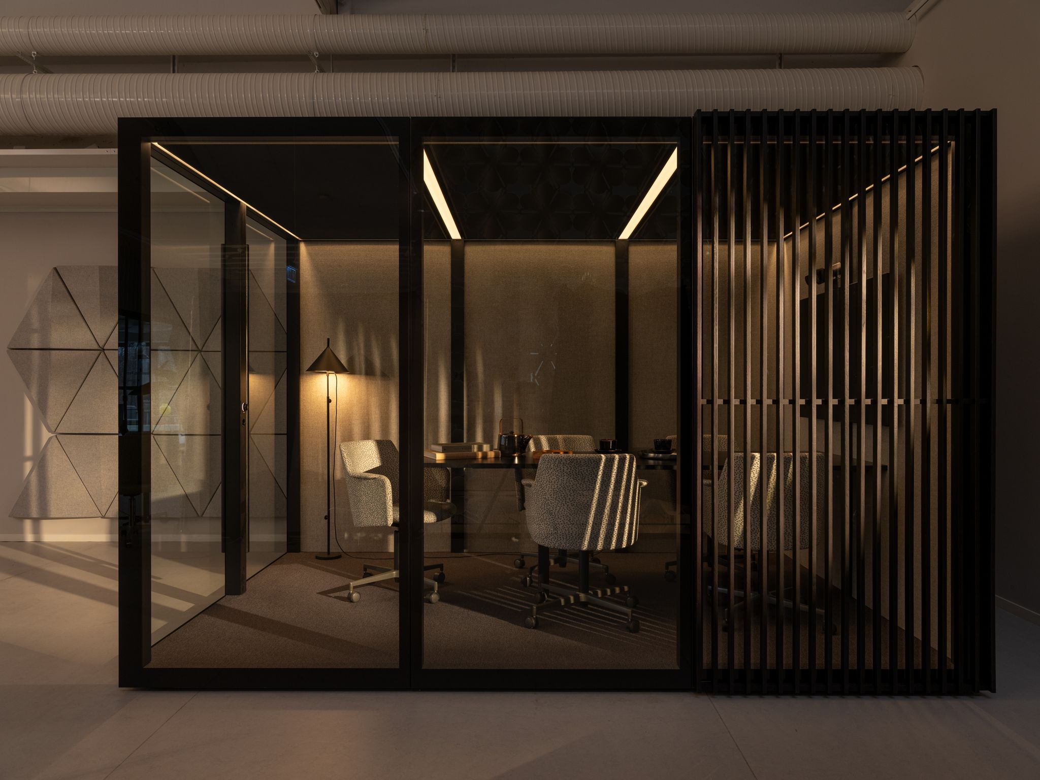 Modern Zen Pod office meeting room with glass walls, soft lighting, and upholstered swivel chairs by Abstracta.