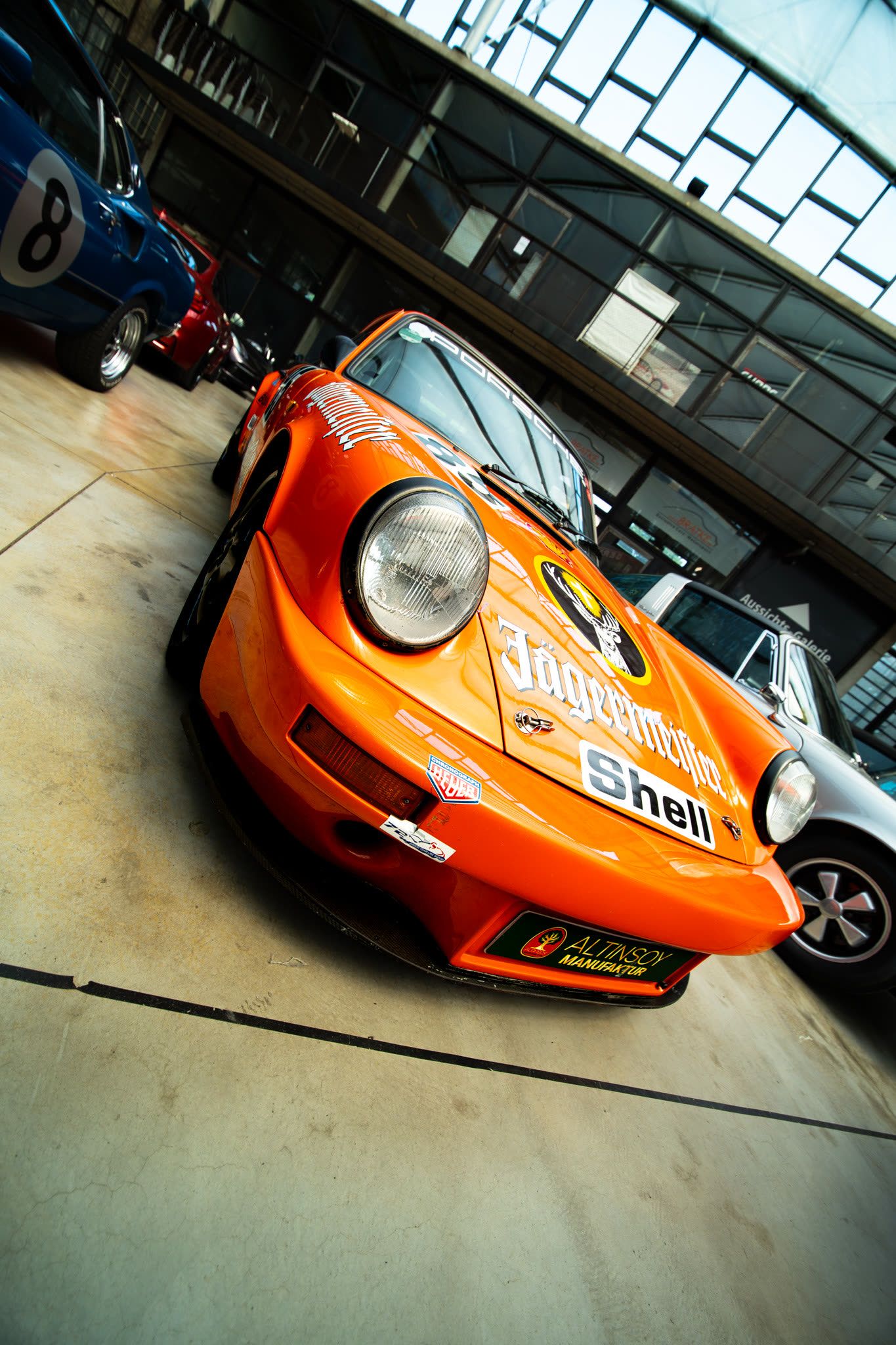 Orange classic Porsche race car in a showroom