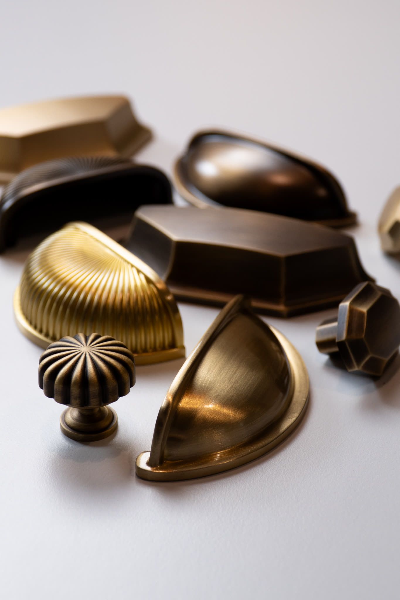 Collection of brass cabinet knobs and cup pulls arranged on a neutral background