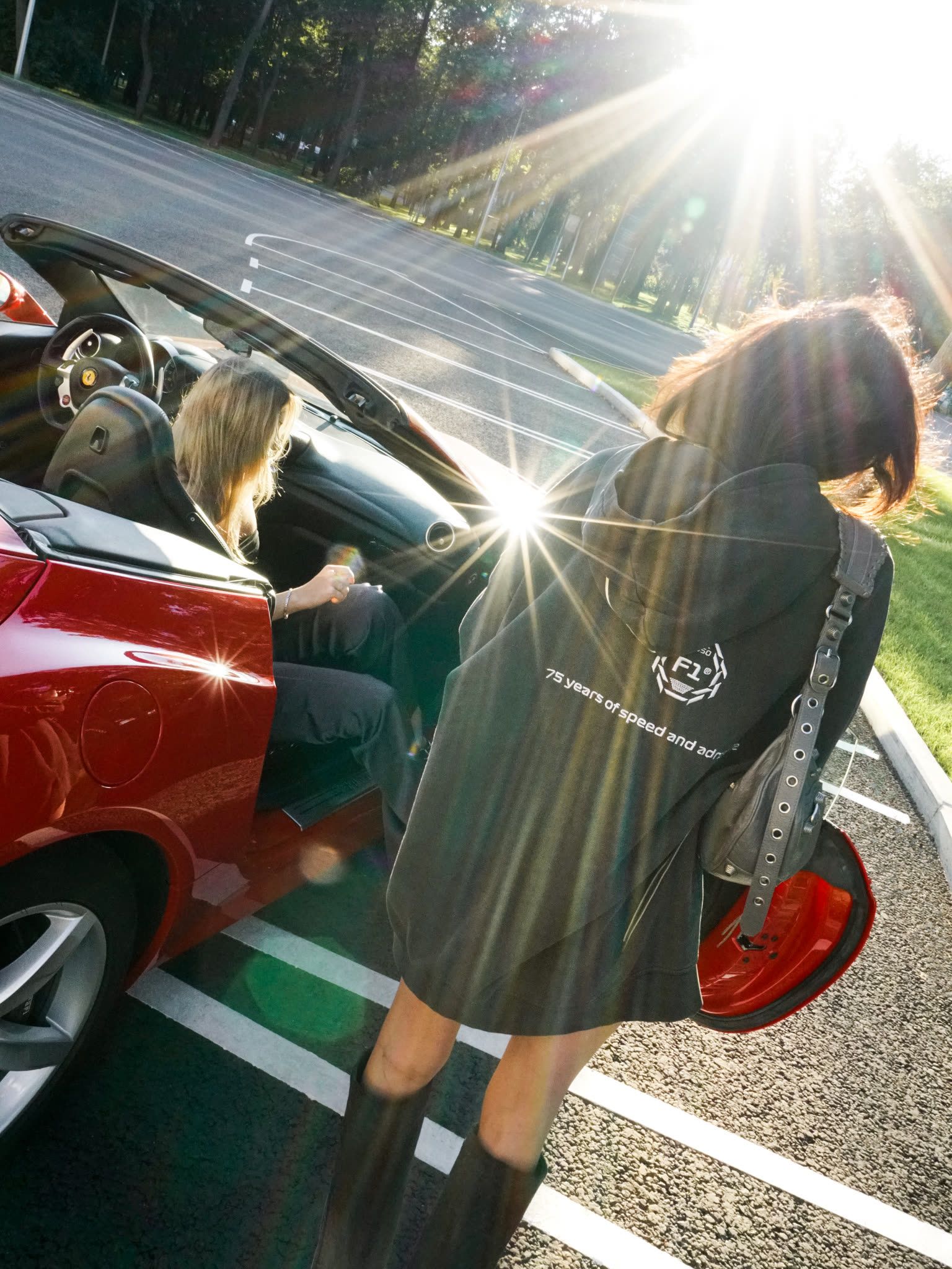 Woman beside a red car in low sunlight