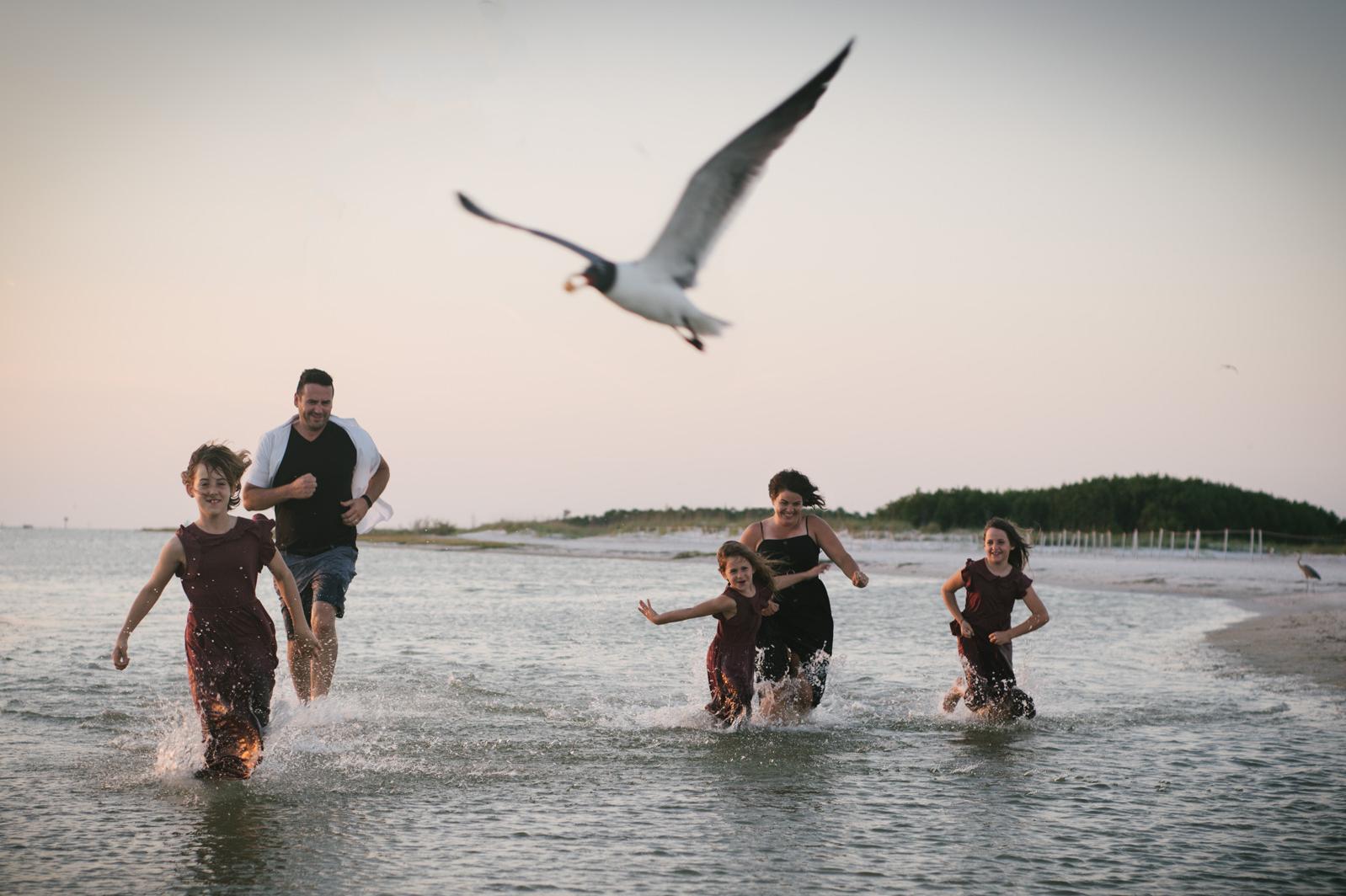 family of three laughing in the a field of tall grass