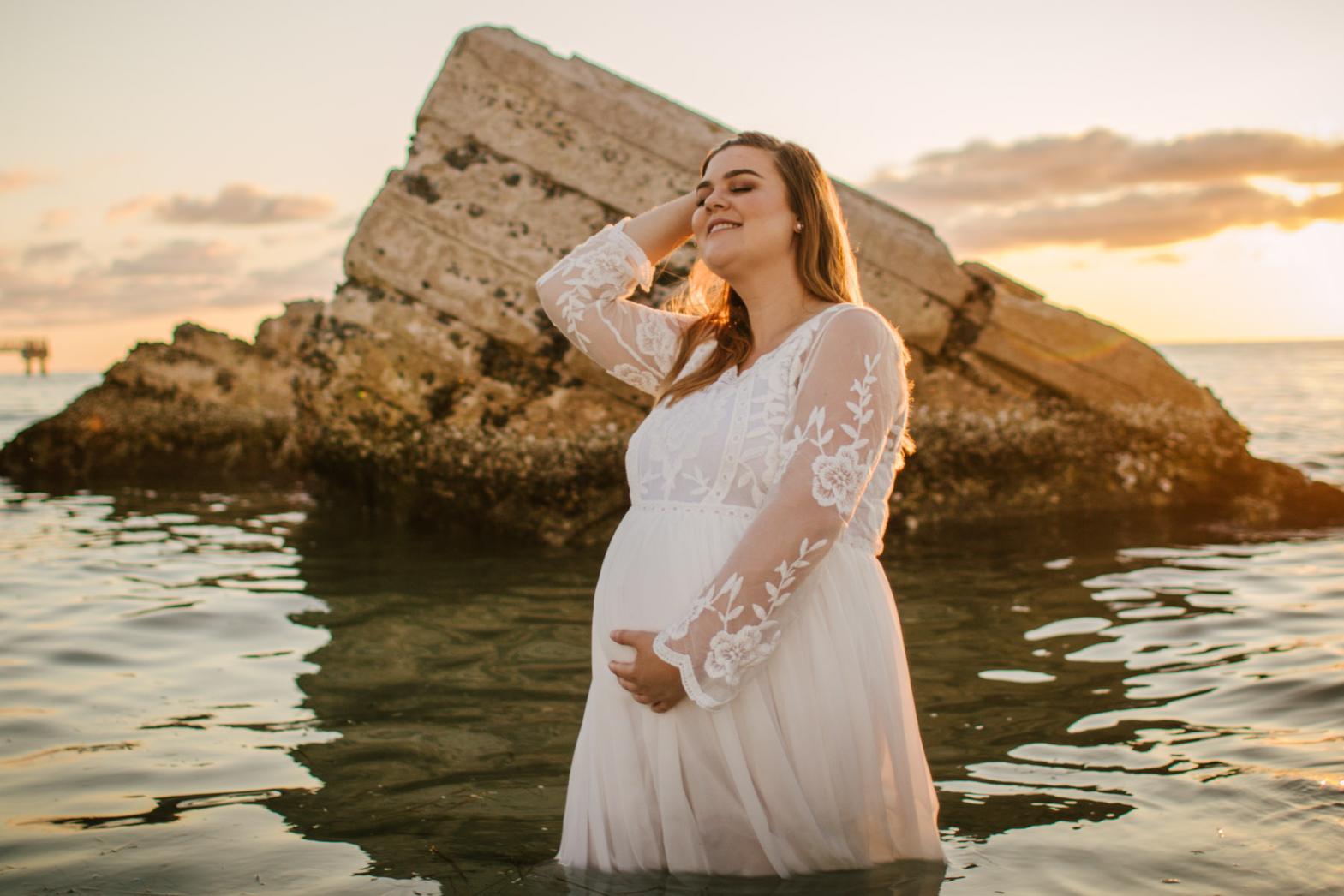 pregnant mama standing in the water at the beach with ruins behind her. St. Pete maternity photographer