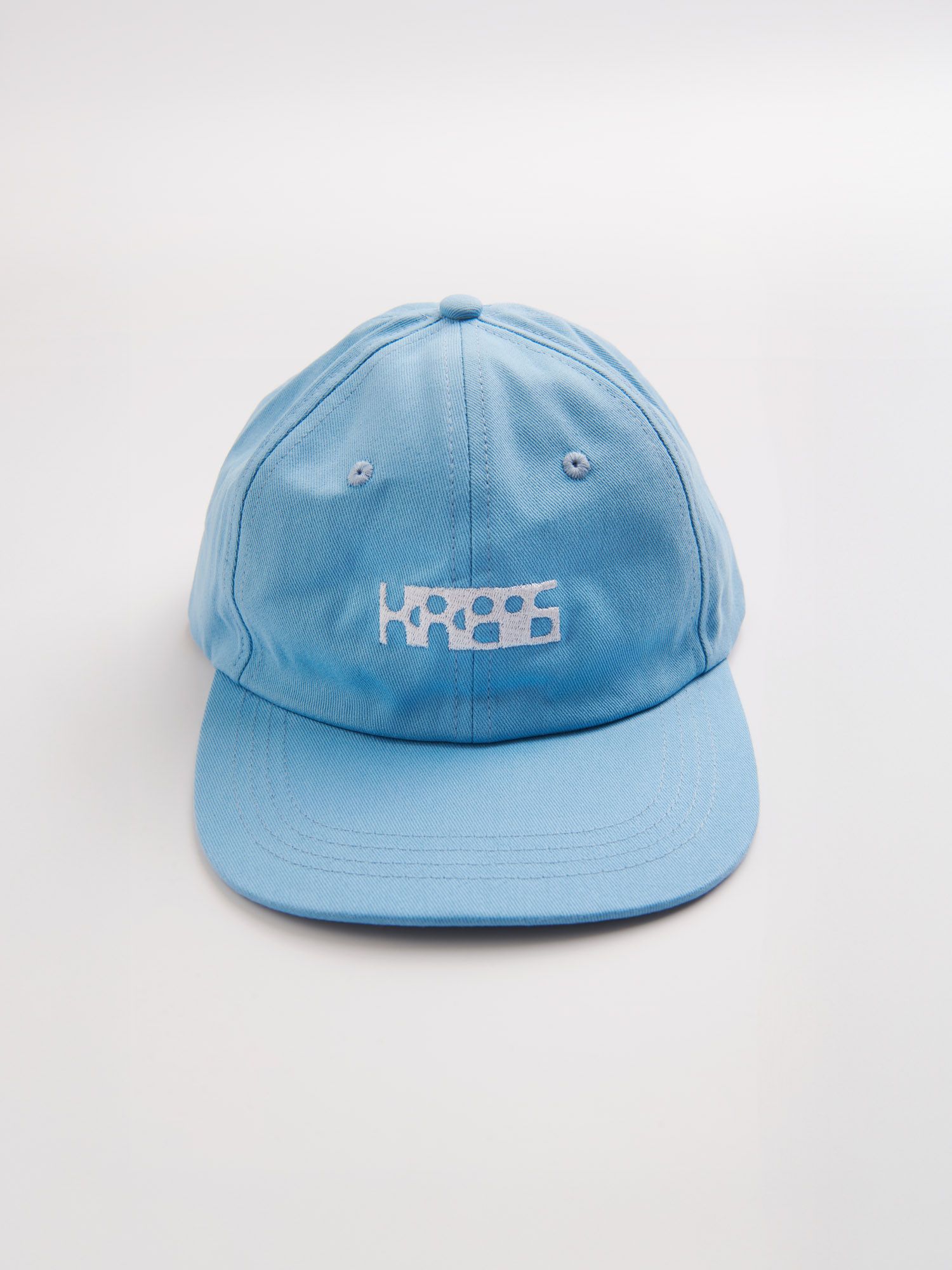 Blue cap with white geometric lettering on a white background