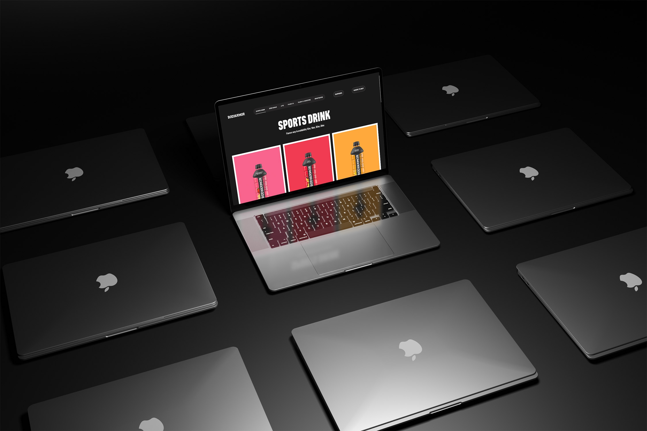 Multiple laptops arranged on a dark surface with one open device displaying the Bodyarmor sports drink product page featuring bold colors and a clean e-commerce layout