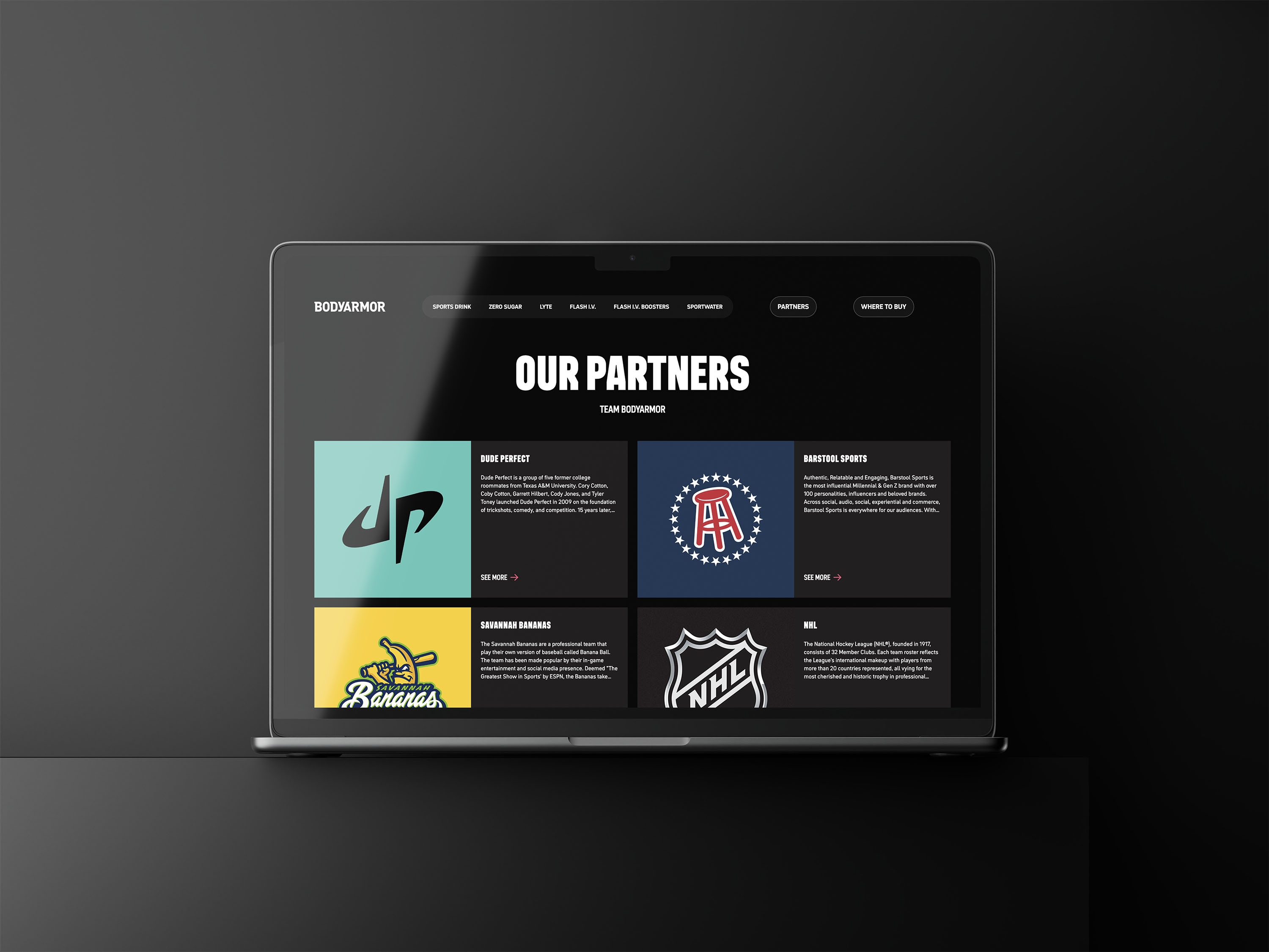 Laptop displaying the Bodyarmor Our Partners webpage featuring brand collaborations including Dude Perfect, Barstool Sports, Savannah Bananas, and the NHL