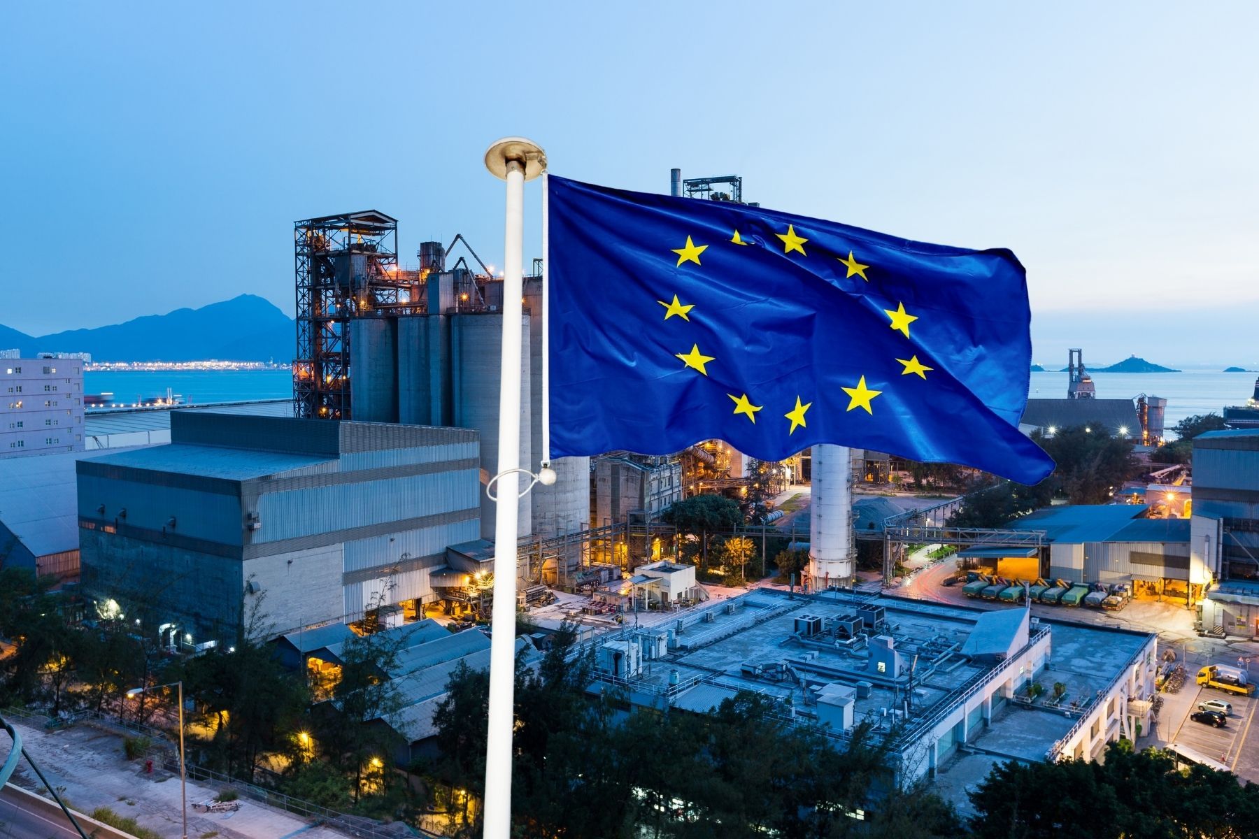 The EU flag in front of a stock image of a steel factory