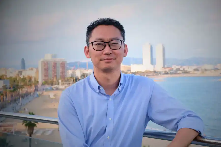 Shawn Xu, partner at Lowercarbon Capital, stands on a balcony in Barcelona, 2026. Credit: Siôn Lawrence-Geschwindt for Impact Loop