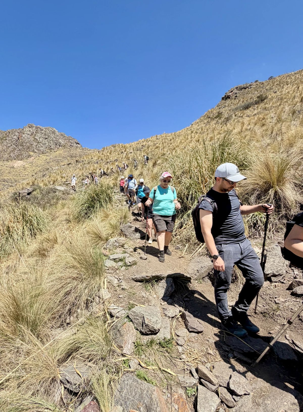 Columna de caminantes bajando por el sendero rocoso de la sierra