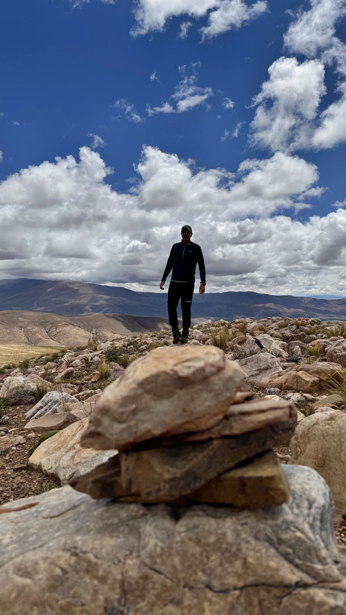 Andinista de pie sobre una apacheta de piedras en la puna de Jujuy