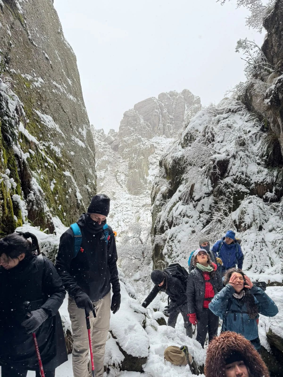 Trekkers entrando a una quebrada estrecha entre paredes de granito nevadas