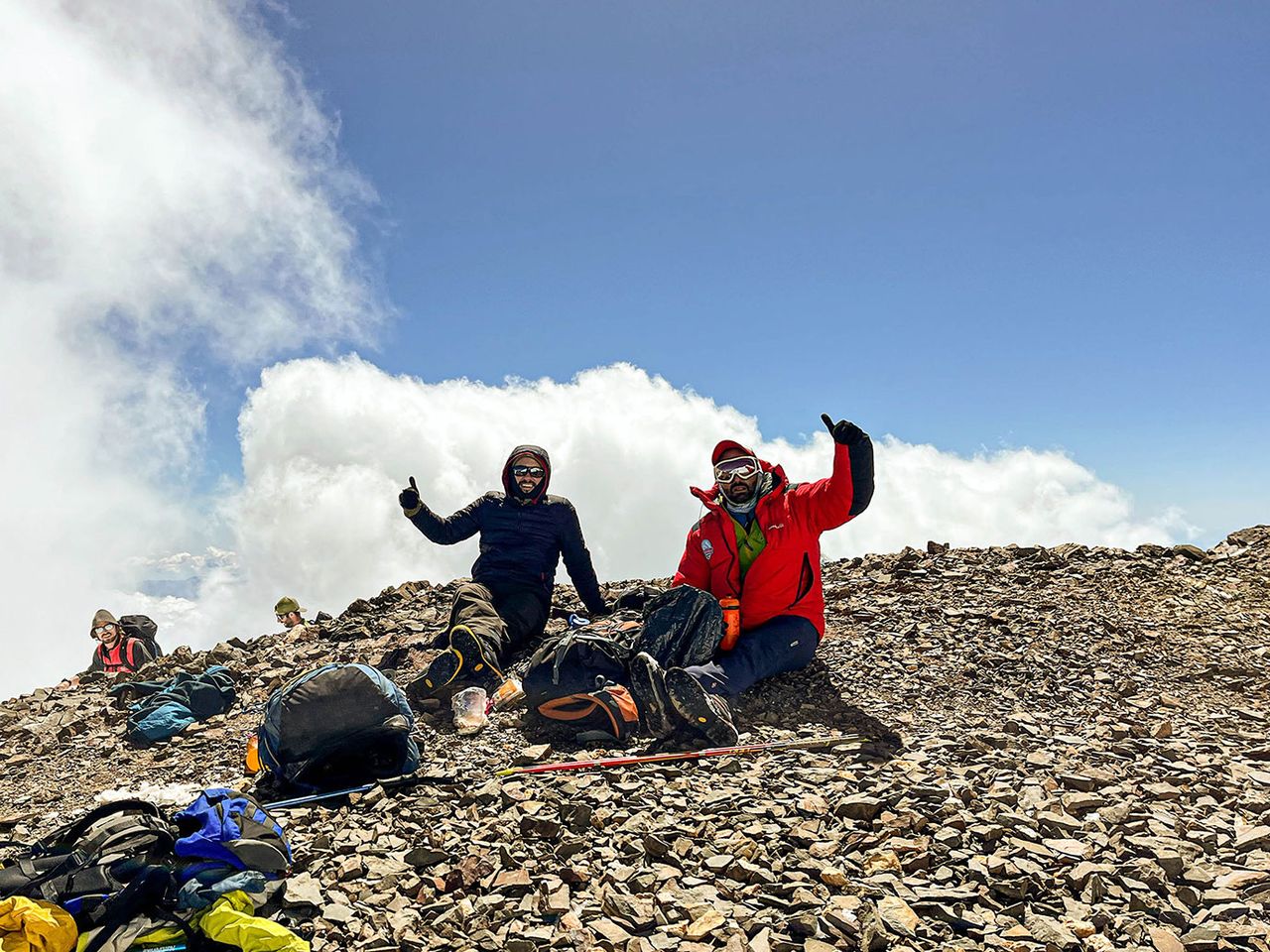 Dos montañistas celebrando en una cumbre por encima de las nubes tras aclimatar a la altura — MONS Actividades de Montaña.