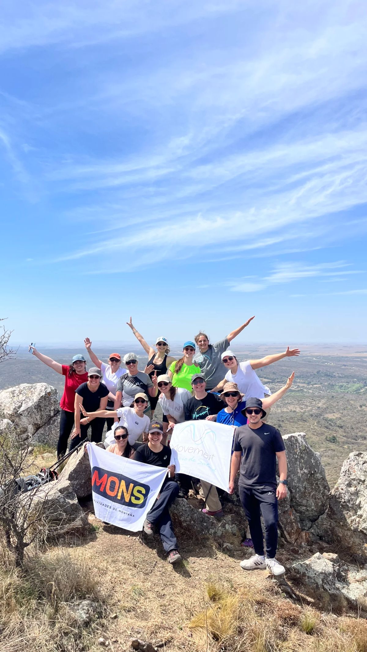 El grupo con la bandera de Mons desplegada en la cumbre de los cerros de Alpa Corral