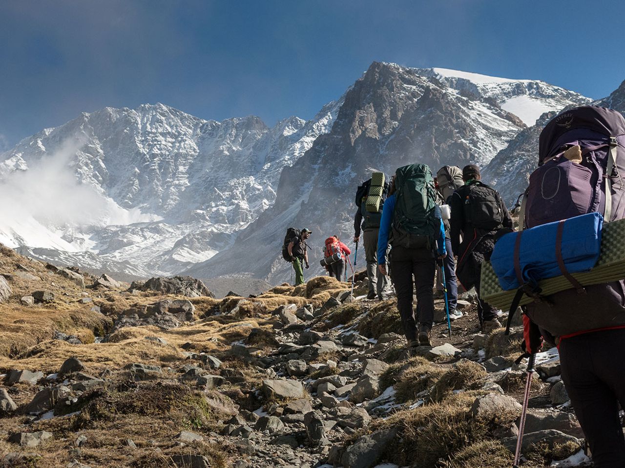 Montañistas ascendiendo al Cerro del Medio en el Cordón del Plata con vista a la cordillera nevada